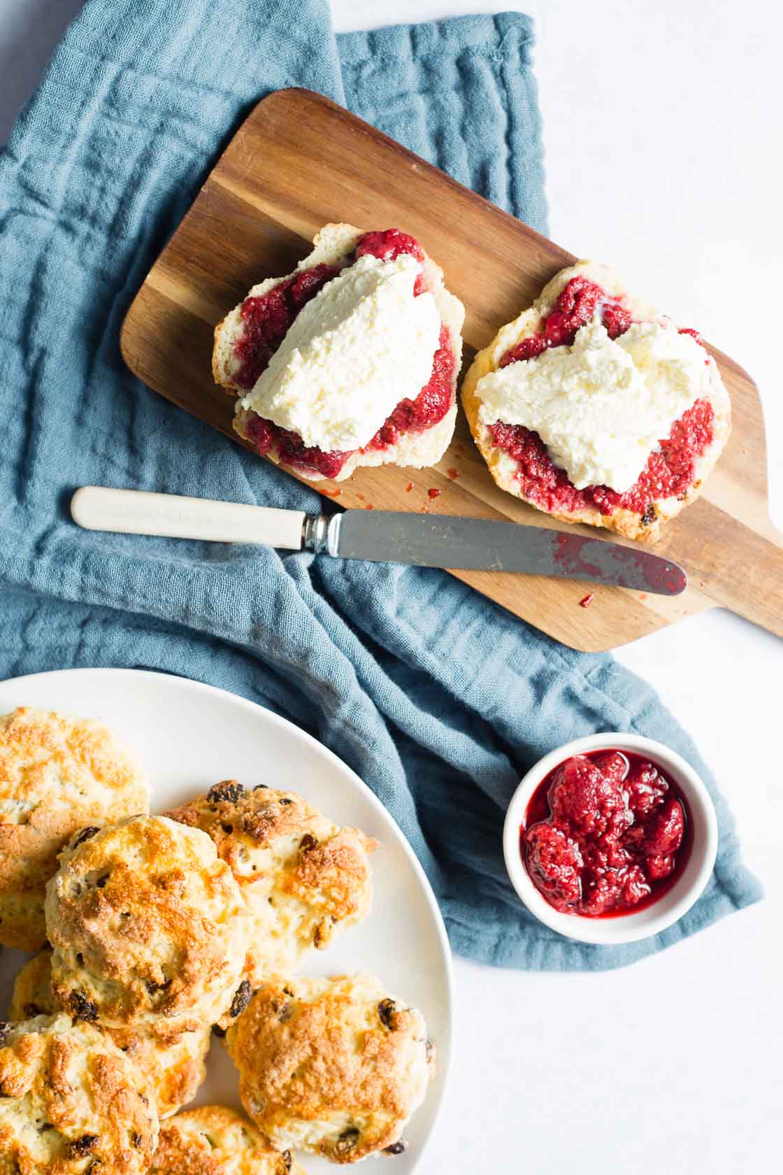 Overhead shot of scones with clotted cream and jam on wooden board