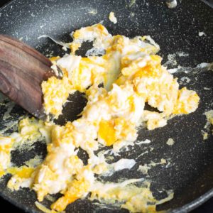 Scrambled Eggs in Skillet mixing with wooden spoon